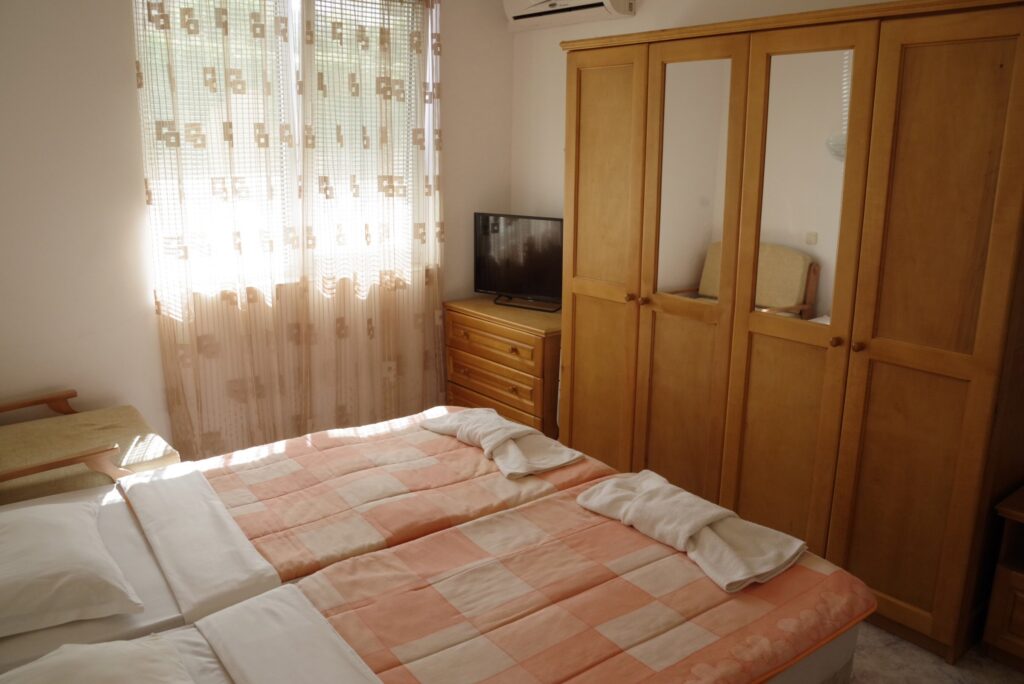 Bedroom 2 in Apartment 1 with twin beds in the middle of the room, a single sofa bed to the right of the beds, wardrobe, cable TV and air-conditioning.
