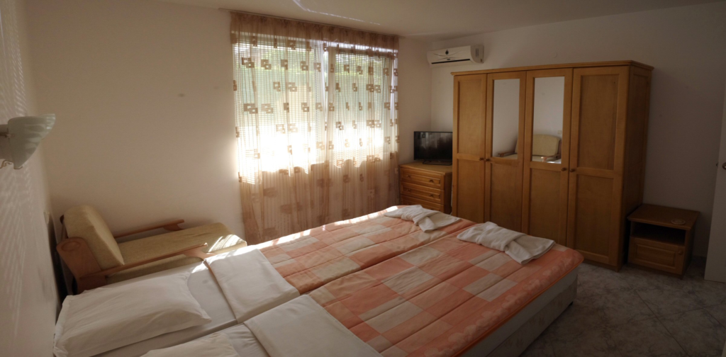 Bedroom 2 in Apartment 1 with twin beds in the middle of the room, a single sofa bed to the right of the beds, wardrobe, cable TV and air-conditioning.