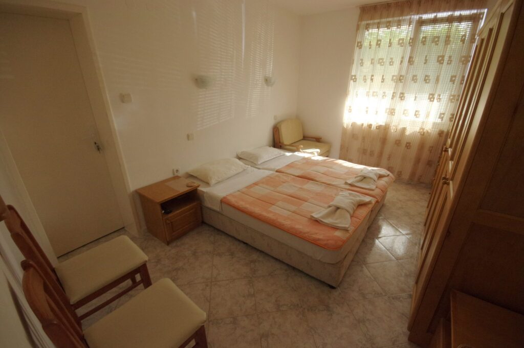 Bedroom 2 in Apartment 1 with twin beds in the middle of the room, a single sofa bed to the right of the beds, wardrobe, cable TV and air-conditioning.