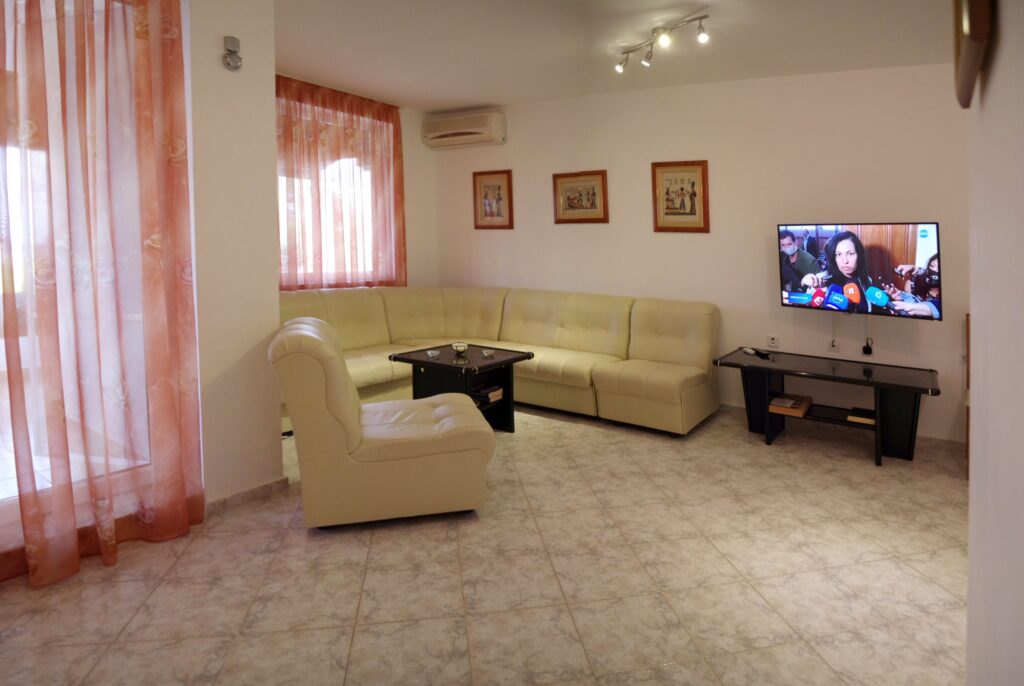 The spacious living Room in Apartment 1 with modular furniture that has a built in double bed and storage area, a coffee table, TV, separate dining area with an extendable table and 8 chairs. And an adjacent fully fitted kitchenette.