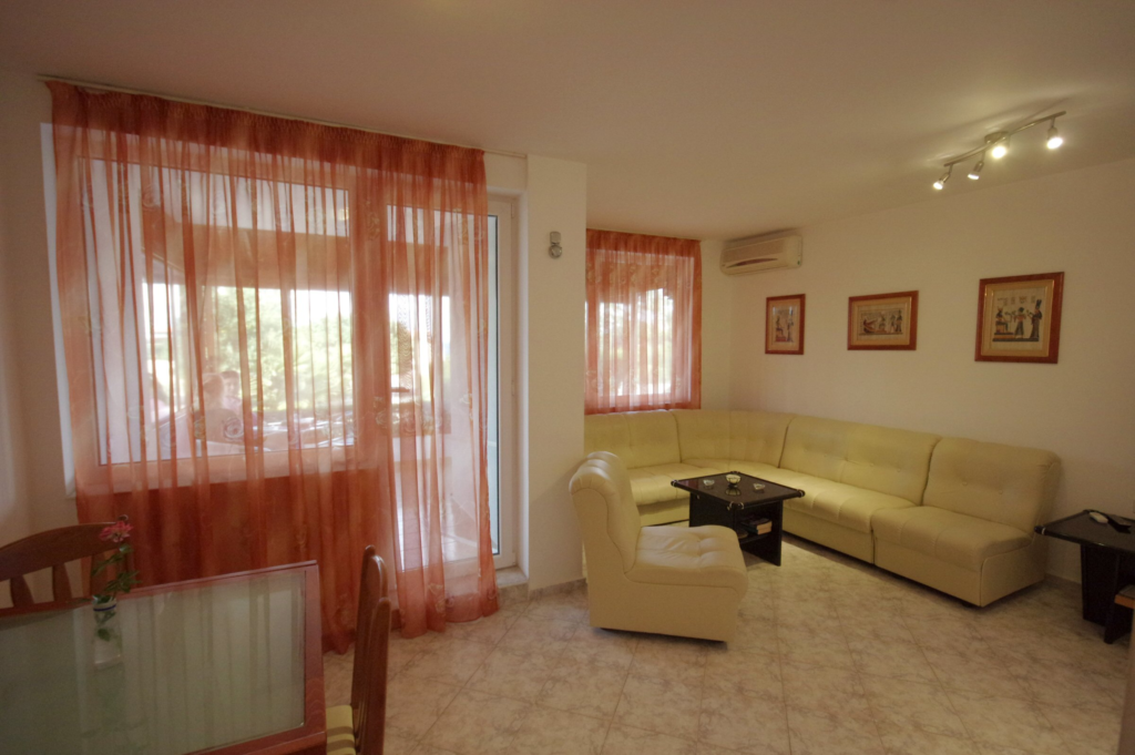 The spacious living Room in Apartment 1 with modular furniture that has a built in double bed and storage area, a coffee table, TV, separate dining area with an extendable table and 8 chairs. And an adjacent fully fitted kitchenette.