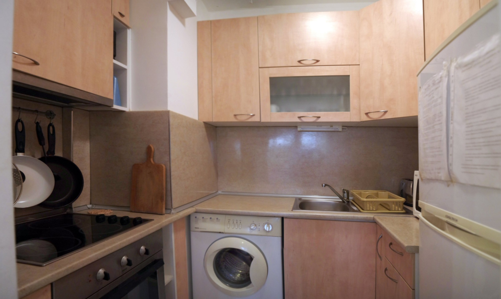 The fully equipped kitchenette in Apartment 1 with a sink, microwave, fridge, washing machine, stoves, oven and all necessary tableware and dinnerware.