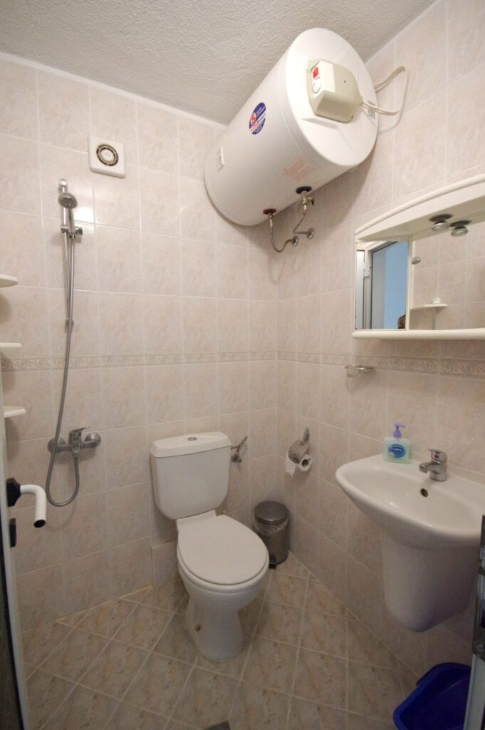 Bathroom 2 in Apartment 1 with a shower, sink, toilet and a toiletries cabinet.