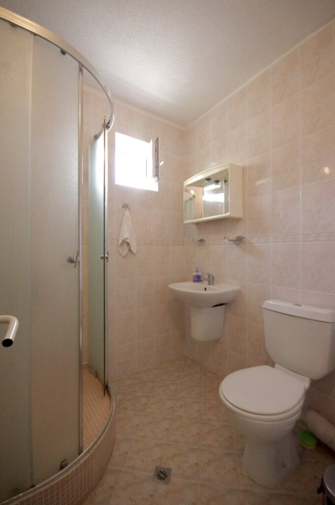Bathroom 1 in Apartment 1 with a shower cabin, sink, toilet and a toiletries cabinet.