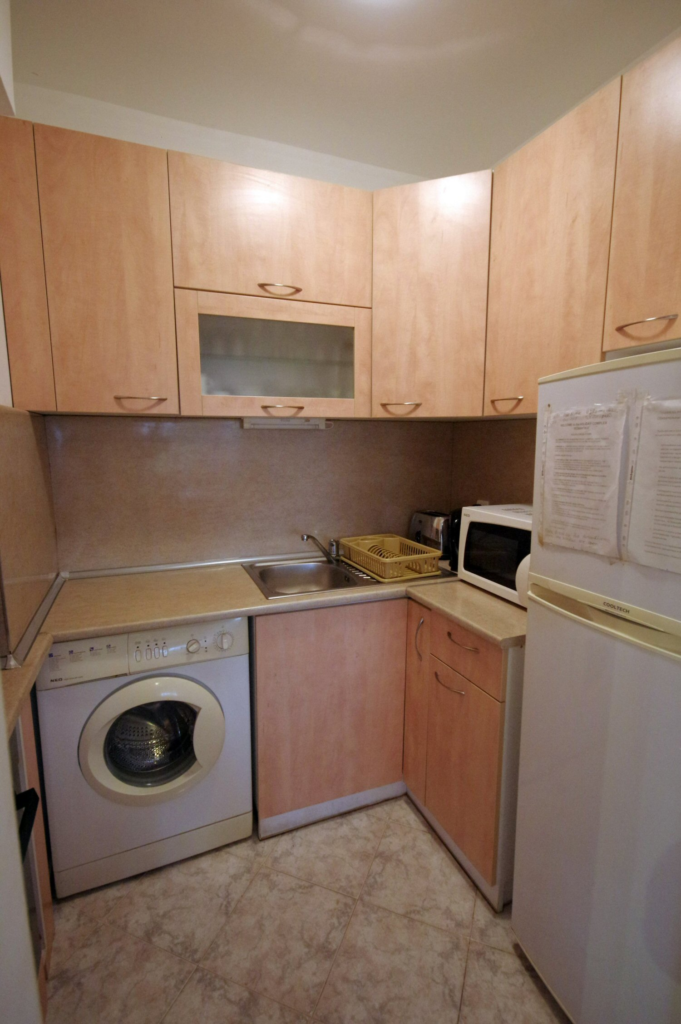 The fully equipped kitchenette in Apartment 1 with a sink, microwave, fridge, washing machine, stoves, oven and all necessary tableware and dinnerware.