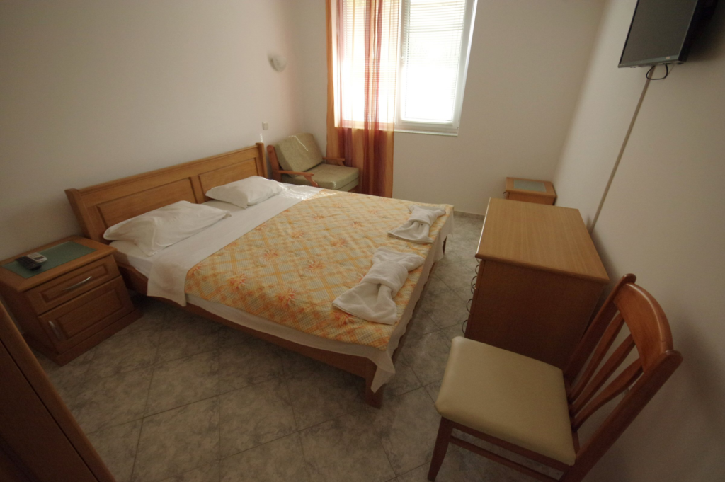 Bedroom 1 in Apartment 2 with a King size bed in the middle of the room, a single sofa bed to the right of the bed, a wardrobe along the left wall, a cable TV and air-conditioning.