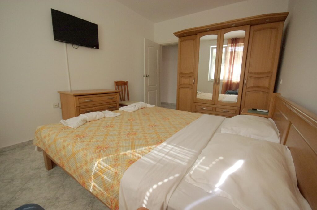 Bedroom 1 in Apartment 2 with a King size bed in the middle of the room, a single sofa bed to the right of the bed, a wardrobe along the left wall, a cable TV and air-conditioning.
