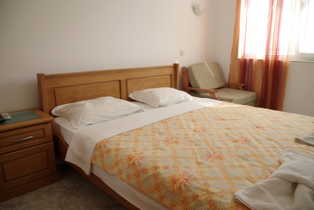 Bedroom 1 in Apartment 2 with a King size bed in the middle of the room, a single sofa bed to the right of the bed, a wardrobe along the left wall, a cable TV and air-conditioning.