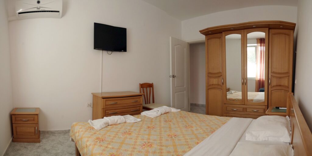 Bedroom 1 in Apartment 2 with a King size bed in the middle of the room, a single sofa bed to the right of the bed, a wardrobe along the left wall, a cable TV and air-conditioning.