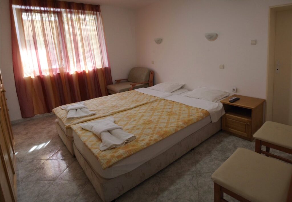 Bedroom 2 in Apartment 2 with twin beds in the middle of the room, a single sofa bed to the right of the beds, wardrobe, cable TV and air-conditioning.