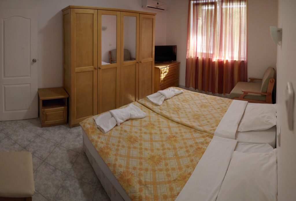 Bedroom 2 in Apartment 2 with twin beds in the middle of the room, a single sofa bed to the right of the beds, wardrobe, cable TV and air-conditioning.