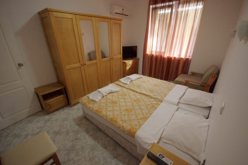 Bedroom 2 in Apartment 2 with twin beds in the middle of the room, a single sofa bed to the right of the beds, wardrobe, cable TV and air-conditioning.