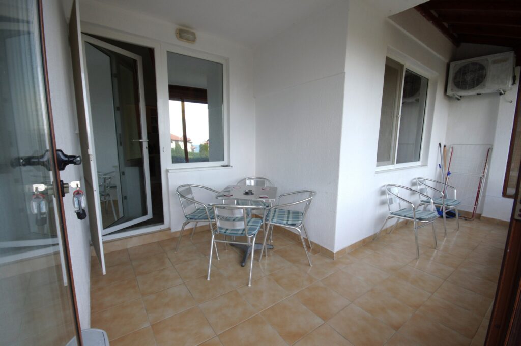 Patio space of Apartment 2 with a table and four chairs, with a relaxing view towards the complex.