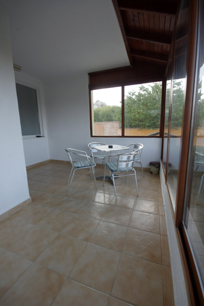 Patio space of Apartment 1 with a table and four chairs, with a relaxing view towards the complex.