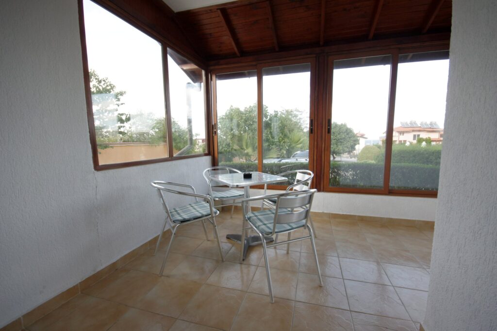 Patio space of Apartment 1 with a table and four chairs, with a relaxing view towards the complex.