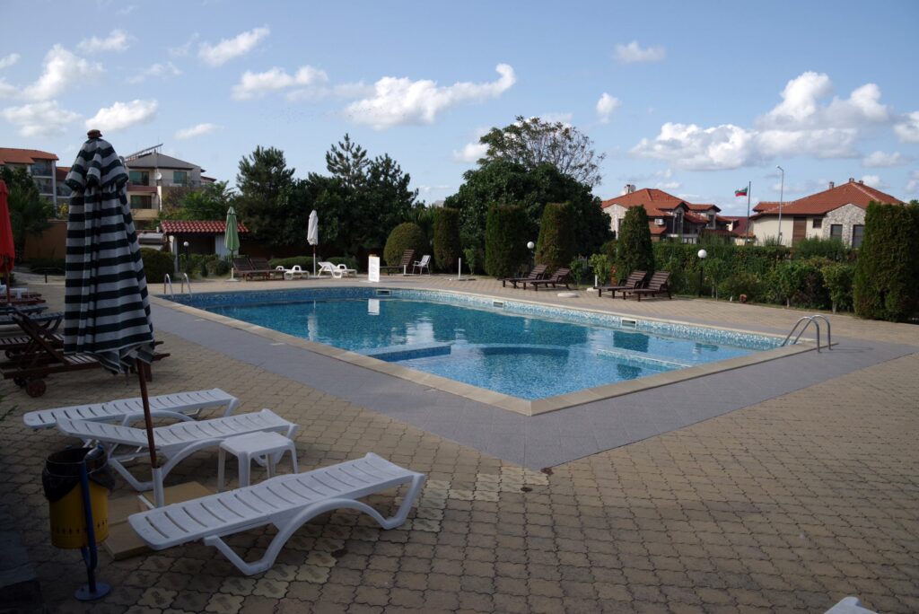 The relaxing outside space of Summer Romantica Apartments, showing the pool, children's pool, lounge chairs area and the nice greenery around the complex.