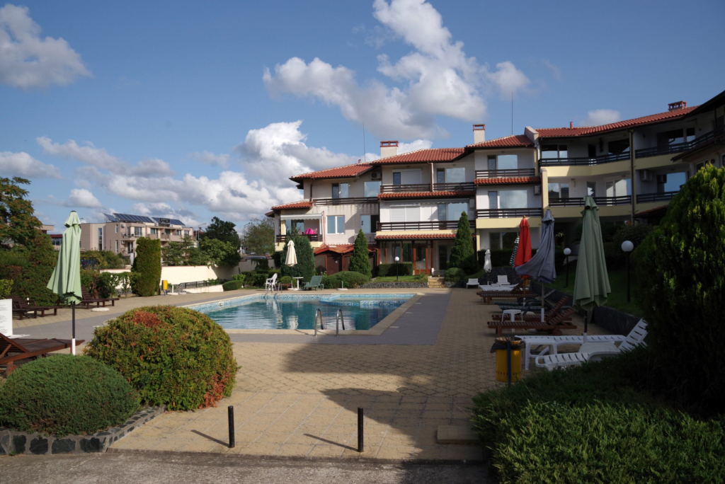 The relaxing outside space of Summer Romantica Apartments, showing the pool, children's pool, lounge chairs area and the nice greenery around the complex.