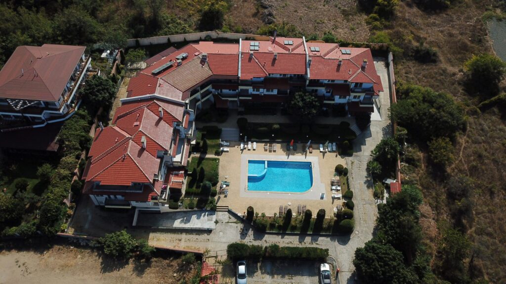A Birds Eye view of Summer Romantica Apartments and the complex space they are located at. Shows the big private pool area that includes a children's pool, lounge chairs, and the private parking space.