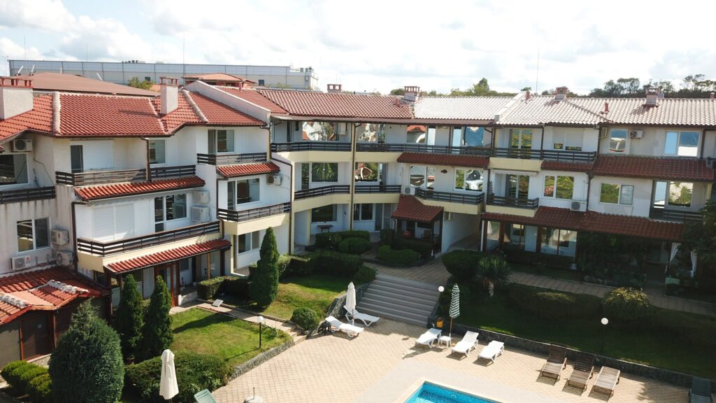 A Birds Eye view of Summer Romantica Apartments and the complex space they are located at. Shows the big private pool area that includes a children's pool, lounge chairs, and the private parking space.
